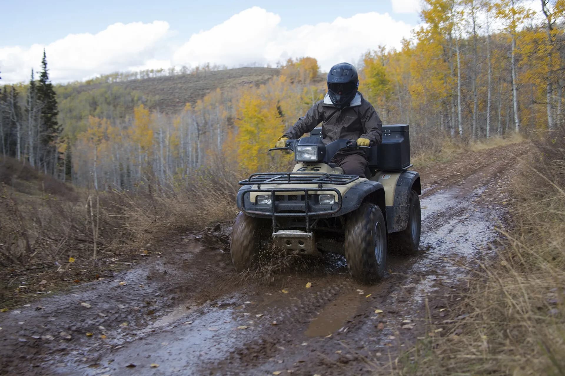 ATV rider on a muddy trail through autumn aspens